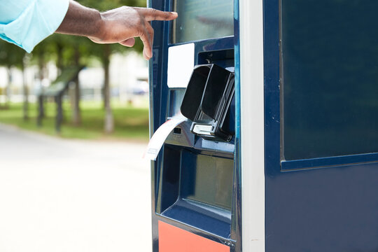 Hand of male commuter using ticket machine on sunny day