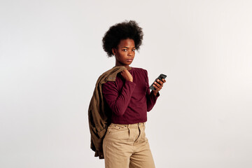 African American girl in brown sweater poses with her smart phone in her hand. - 462724400