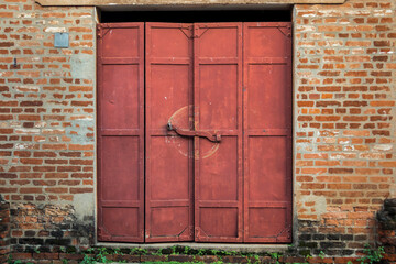 An old rusty metal door between exposed brick walls