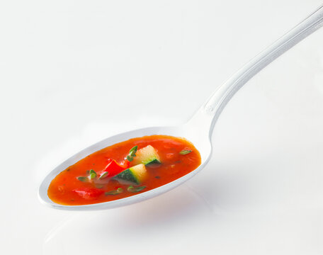 Studio shot of spoon of tomato soup with vegetables