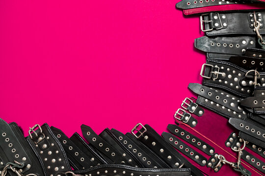 Pink color banner with black leather bracers and metal rivets for shackling hands or legs and performing sexual games. BDSM subject. Background for advertising adult products and sex toy store