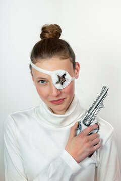 Portrait of teenage girl with revolver wearing eye patch