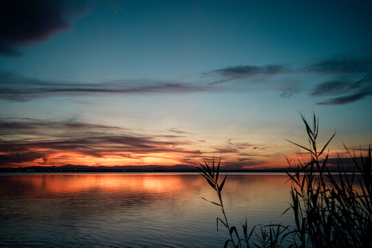Scenic view of lake against dramatic sky during sunset