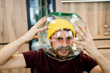 Frustrated businessman screaming while wearing fishbowl in modern office