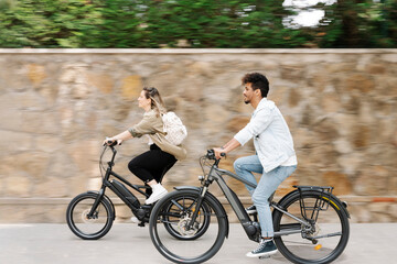 Couple riding electric bicycles on road in city