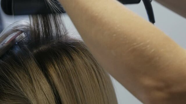 Alignment of hair curls with a special hot ironing. Blond long hair of a young woman