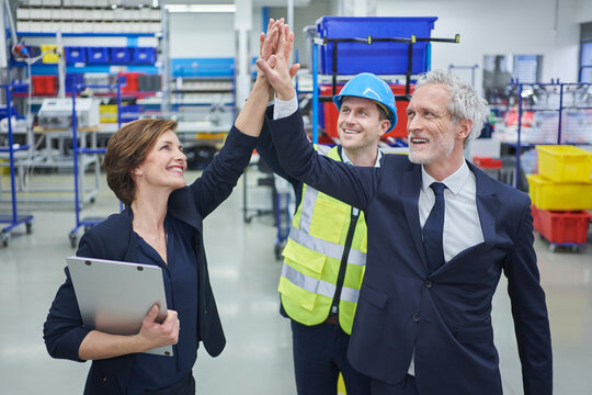 Happy managers and supervisor giving high-five in industry