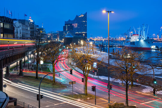 Germany, Hamburg, Vehicle light trails stretching along harbor street at dawn with Elbphilmarmonie in background