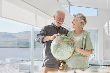 Happy senior couple with globe in a luxury villa