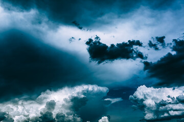 Obraz premium White clouds against a dark bright blue sky. Cloudy wallpaper for news about weather forecast. Before a thunderstorm and hurricane or storm. The power and strength of nature. Air element. Religion