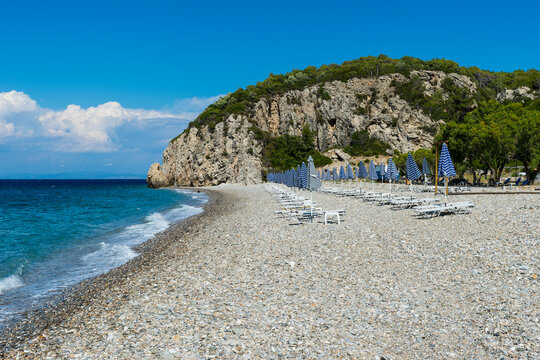 Greece, North Aegean, Rows of beach umbrellas and empty deck chairs on Tsambou beach in summer