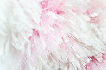 the closeup view of the artificial fur in the uneven dyed color of white and pink. messy yet fluffy surface material for background.