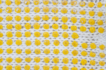 the details of a white fabric knit texture with yellow dots over it. a series of woven threads that has been becoming a textile material.