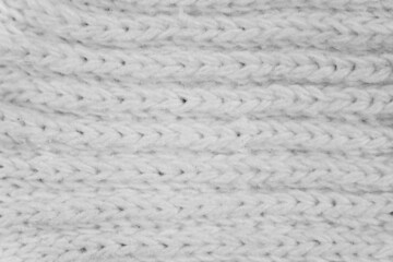 a fabric knit texture in white color. a series of woven threads that has been becoming a textile material. the details of the knitted pattern.