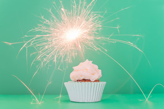 Single cupcake decorated with burning sparkler