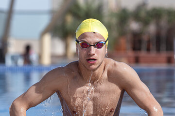Determined male swimmer coming out from pool at tourist resort, Dubai, United Arab Emirates
