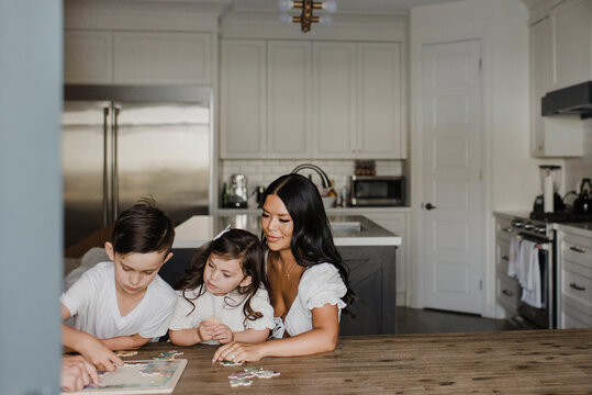 Smiling Parents Solving Puzzle With Children Over Table At Home