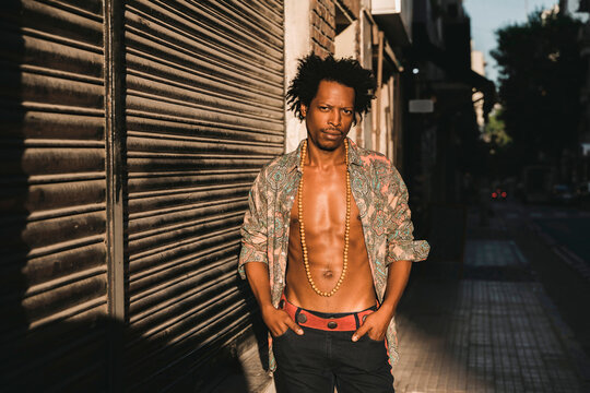 Confident retro man wearing unbuttoned shirt while standing on sidewalk by shutter