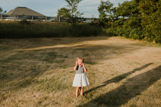 Crying little girl standing alone on a meadow