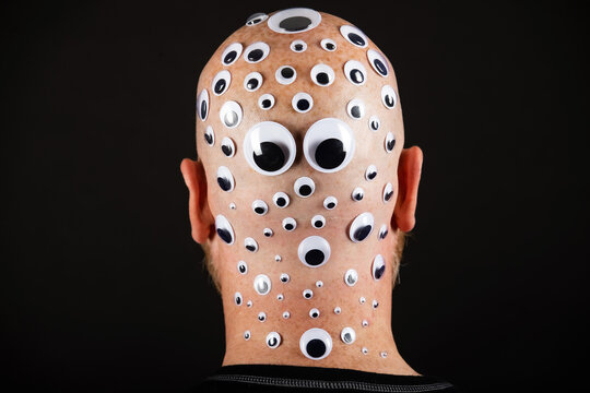 Bald man with head covered in googly eyes