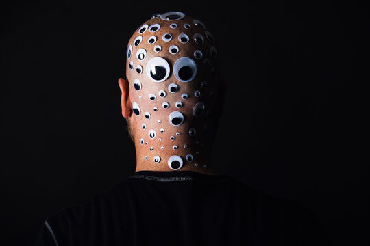 Bald man with head covered in googly eyes