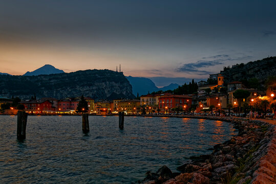 Italy, Trentino, Torbole, Lake Garda, Promenade and town illuminated at dusk