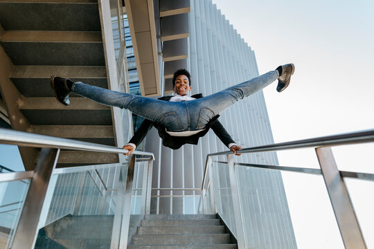Happy male professional doing splits on staircase railing