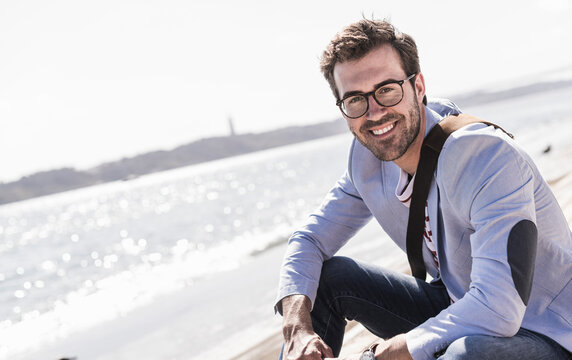 Portrait of happy young man sitting on the waterfront