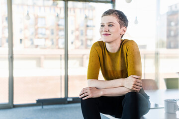 Smiling businesswoman sitting on desk in office
