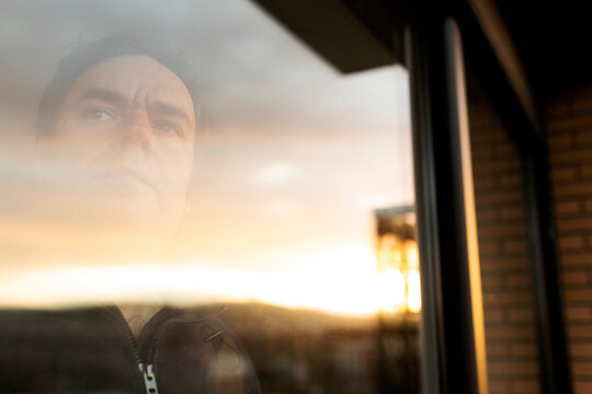 Portrait of serious mature man looking out of window at sunset