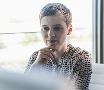 Close-up of thoughtful businesswoman with short hair sitting in office