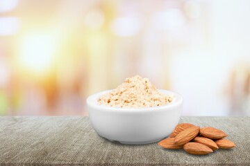 Almond flour in the bowl and almonds nut on the desk
