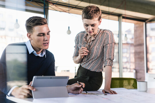 Businessman explaining document to female coworker on desk in office