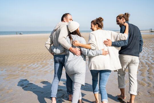 Family With Arms Around Each Other Walking At Beach