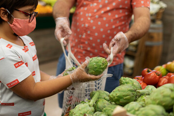 Son with mask and gloves taking artichoke
