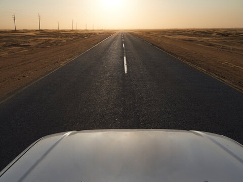 Car on a tarmac road in the desert at sunset, Solitaire area, Namibia