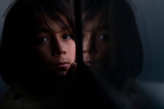 Boy looking at camera at mirrored in window pane at home