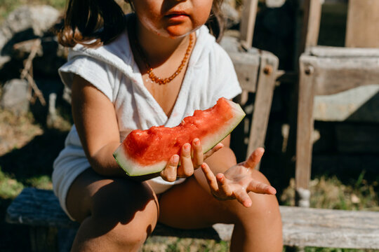 Girl eating watermelon while sitting on log