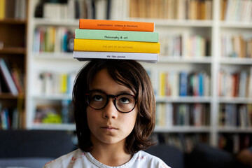 Portrait of boy balancing stack of books on his head