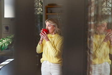 Thoughtful mature woman drinking tea in kitchen