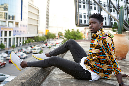Young man in patterned shirt sitting on roof terrace in the city, Maputo, Mozambique