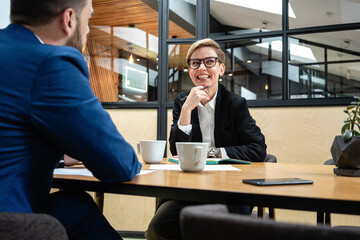 Smiling businesswoman sitting with male executive in board room during job interview