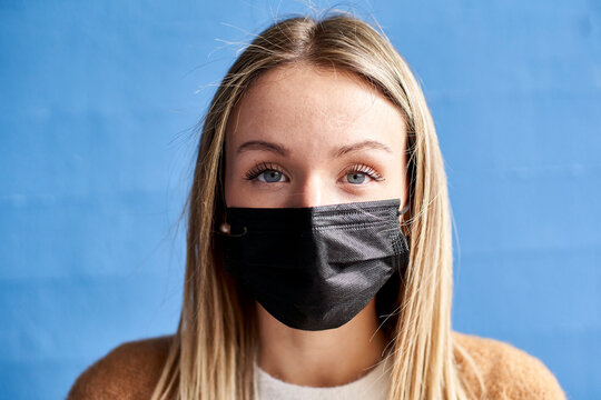 Young woman with protective face mask against wall
