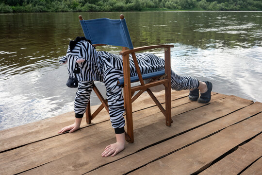 Boy in zebra costume exercising on chair over boardwalk