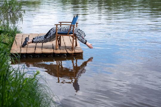 Boy wearing zebra costume exercising on chair by lake