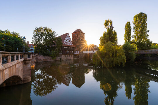 Germany, Bavaria, Nuremberg, Weinstadel and Wasserturm reflecting in river Pegnitz at sunset