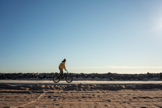 Clear sky over boy riding BMX along empty road