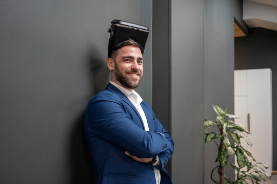 Smiling confident businessman with virtual simulation headset standing at creative office