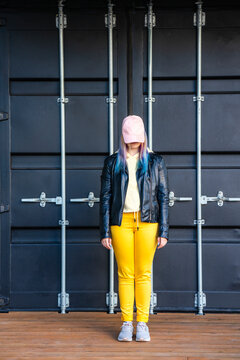 Portrait of young woman with dyed hair in front of black container