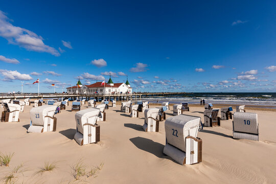 Germany, Mecklenburg-Western Pomerania, Heringsdorf, Hooded beach chairs on empty beach with Ahlbeck Pier in background
